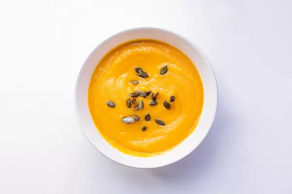 Aufsicht - Eine Schale Kürbiscremesuppe mit Kürbiskernen auf weißem Hintergrund