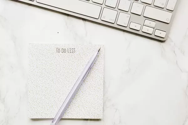 Aufsicht einer To-Do-Liste mit Stift und Tastatur auf Marmor