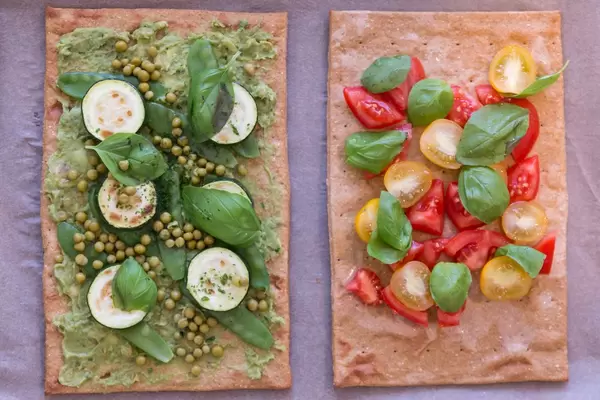 Aufsicht - Lizza Pizza mit Chia-Vegan-Leinsamen Pizzaboden mit Frischen Kirschtomaten und Zucchini, Erbsen und Basilikum belegt