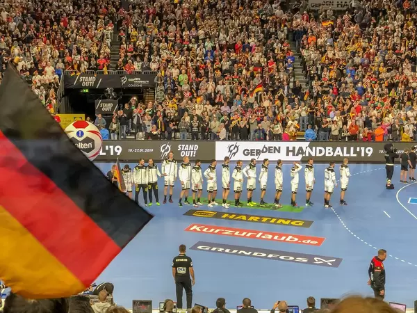 Aufstellung der Deutschen Handballmannschaft in einer Reihe, im Hintergrund Fans auf Tribüne