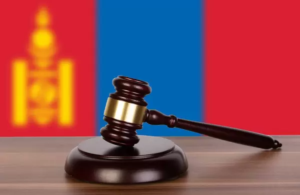 Auktionshammer / Richterhammer auf einem Holzuntergrund, vor der Flagge der Mongolei