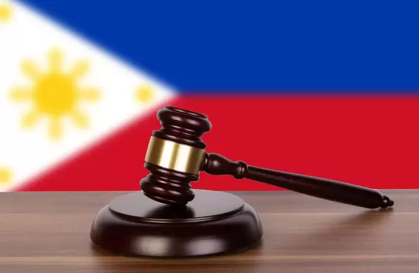 Auktionshammer / Richterhammer auf einem Holzuntergrund, vor der Flagge der Philippinen