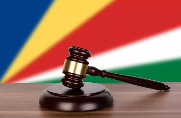 Auktionshammer / Richterhammer auf einem Holzuntergrund, vor der Flagge der Seychellen