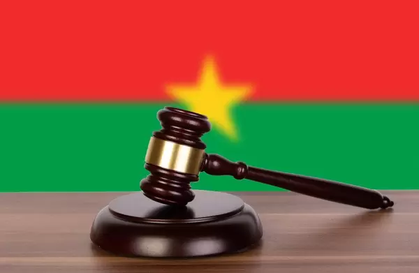 Auktionshammer / Richterhammer auf einem Holzuntergrund, vor der Flagge von Burkina Faso