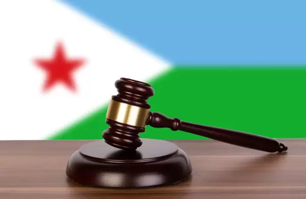 Auktionshammer / Richterhammer auf einem Holzuntergrund, vor der Flagge von Dschibuti