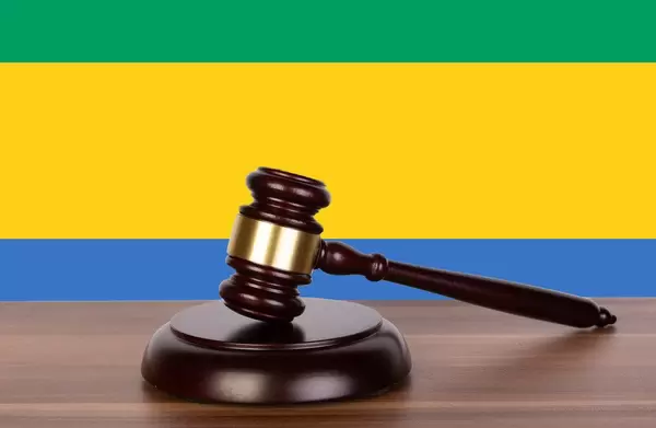 Auktionshammer / Richterhammer auf einem Holzuntergrund, vor der Flagge von Gabun