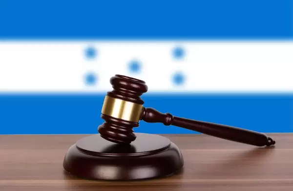 Auktionshammer / Richterhammer auf einem Holzuntergrund, vor der Flagge von Honduras