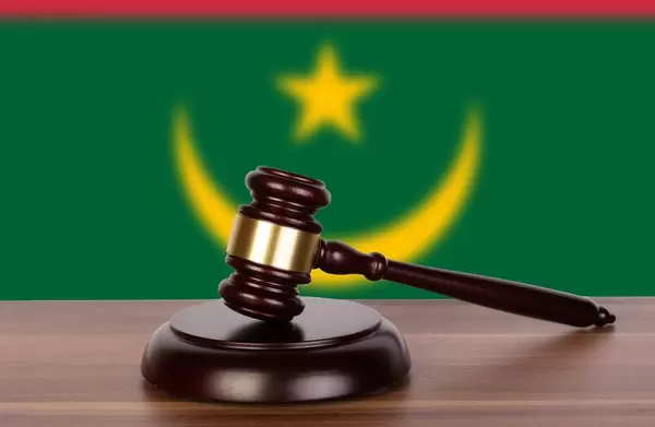 Auktionshammer / Richterhammer auf einem Holzuntergrund, vor der Flagge von Mauretanien