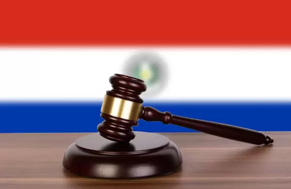 Auktionshammer / Richterhammer auf einem Holzuntergrund, vor der Flagge von Paraguay