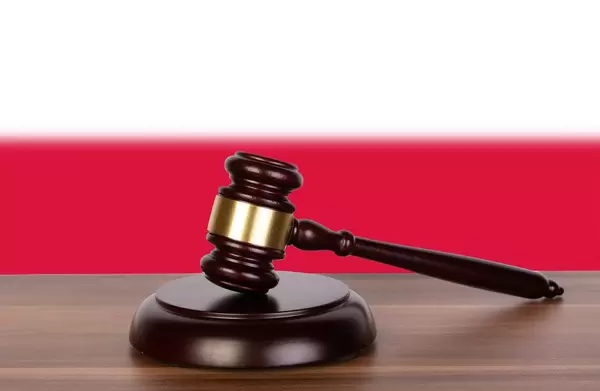 Auktionshammer / Richterhammer auf einem Holzuntergrund, vor der Flagge von Polen