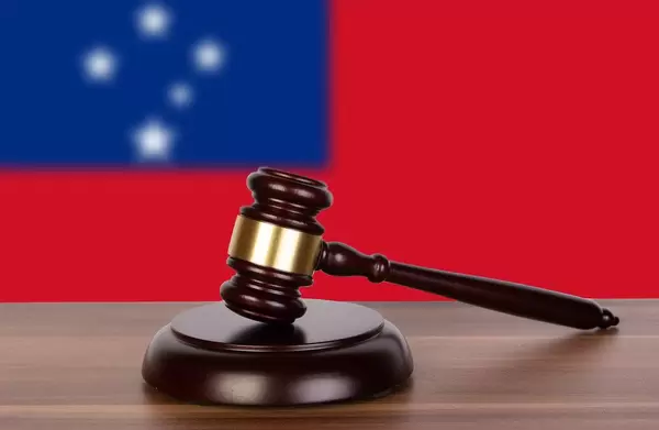 Auktionshammer / Richterhammer auf einem Holzuntergrund, vor der Flagge von Samoa