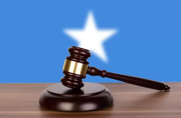 Auktionshammer / Richterhammer auf einem Holzuntergrund, vor der Flagge von Somalia