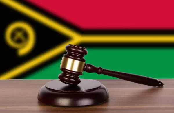 Auktionshammer / Richterhammer auf einem Holzuntergrund, vor der Flagge von Vanuatu