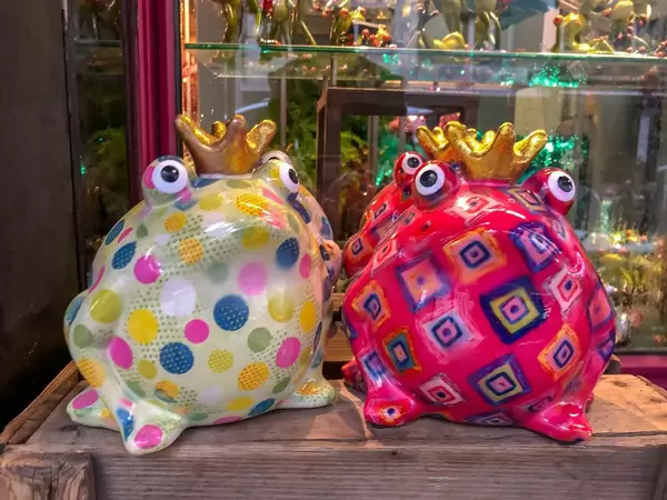 Aus Porzellan gefertigte, bunte Froschkönige auf Holztisch
