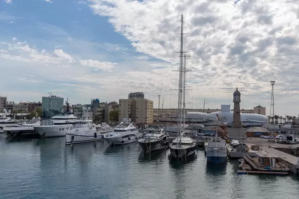 Ausblick von der Rambla de Mar Brücke auf Jachten und Luxusboote im Hafen Port Vell mit Turmuhr in Barcelona, Spanien