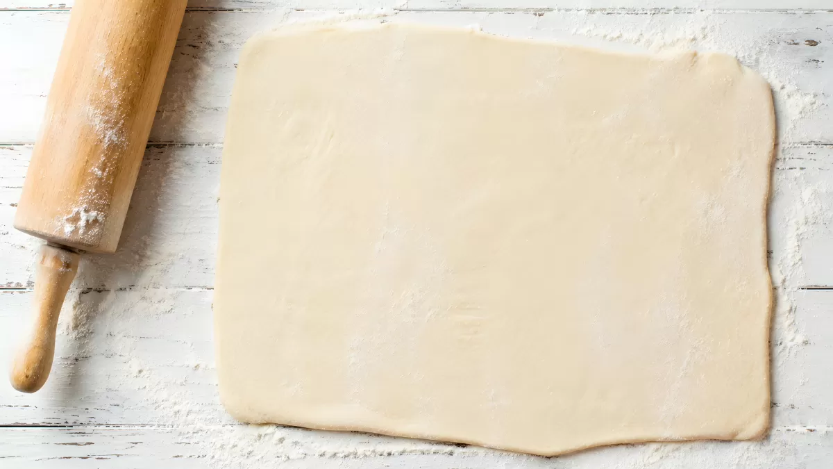 Ausgerollter Hefeteig auf bemehlter Holzfläche