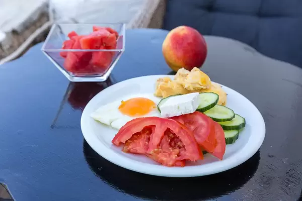 Ausgewogene Mahlzeit mit frischem Gemüse, Spiegelei, Fetakäse, Apfel und geschnittener Wassermelone, auf der griechischen Insel Paros