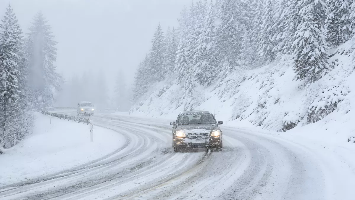 Auto fährt bei Schneesturm auf verschneiter Bergstraße