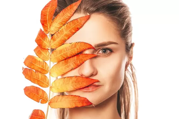 Autumn bright leaf covers half of the girl's face