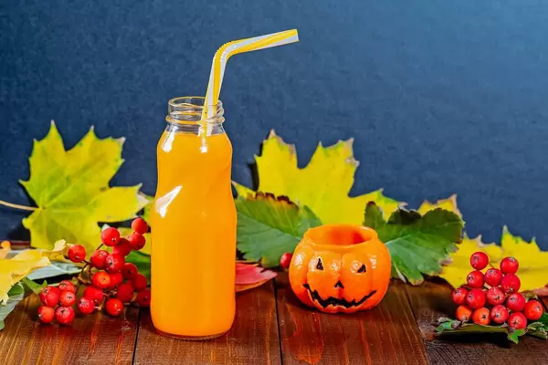 Autumn composition with a bottle of juice and candles-pumpkin