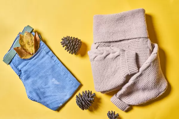 Autumn wears - jeans and knitted sweater on yellow