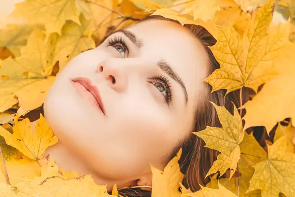 Autumn woman portrait. Beauty model girl with autumnal yellow leaves