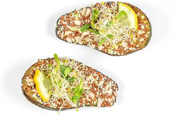 Avocado halves stuffed with microgreens and a mixture of seeds, top view