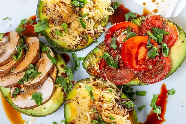 Avocado halves stuffed with mushrooms, cheese, tomatoes and herbs. Top view (Flip 2019)