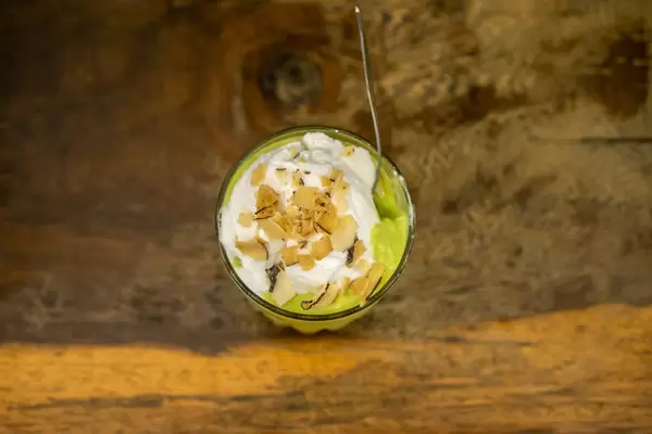 Avocado Kokosnuss Eiscreme mit Mandelblättchen im Glas mit Löffel von oben fotografiert