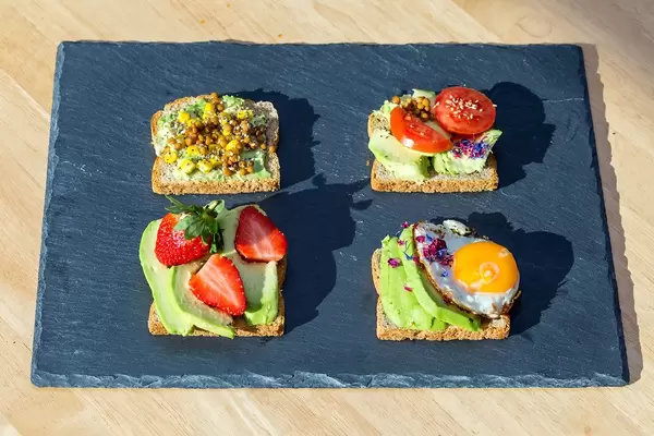Avocado toasts with different toppings: lentils, strawberries, tomatoes and egg