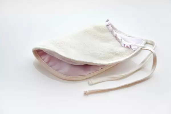 Baby-Lätzchen aus flauschigem Stoff  in weiß und rosa  vor weißem Hintergrund