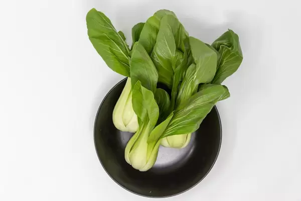 Baby Pak Choi on black plate on white background
