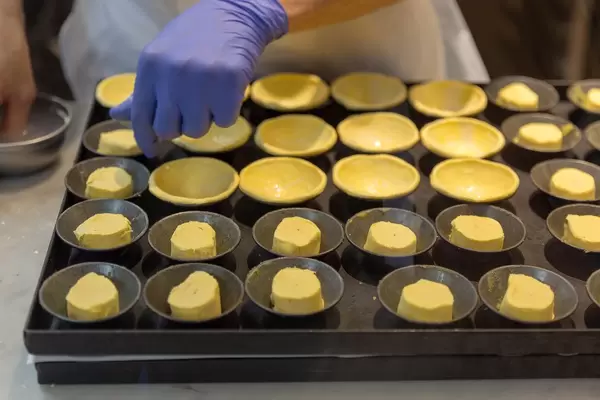 Bäckerin mit Handschuhen stellt Gebäck her