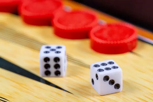 Backgammon-Spiel. Spielwürfel liegen auf dem Backgammonbrett vor dem Hintergrund von Spielsteinen