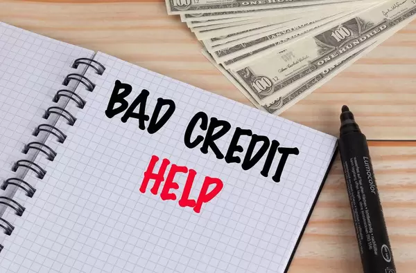 Bad credit help text in notebook and Dollar banknotes on wooden table