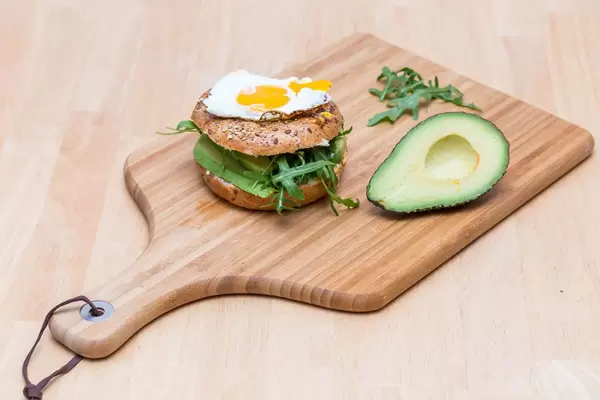 Bagel mit Avocado, Rucola, Humus und Spiegelei