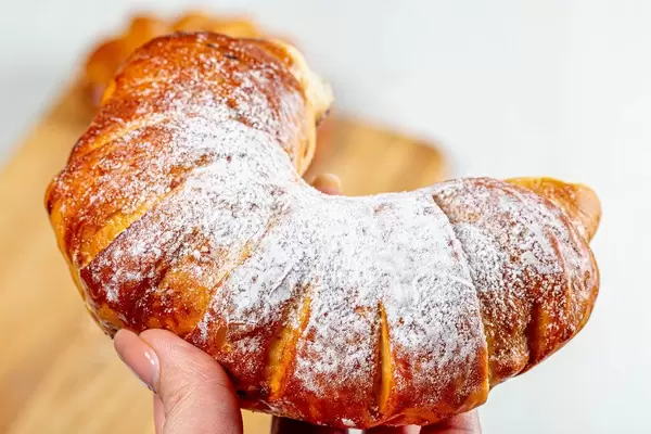 Bagel with powdered sugar in a woman's hand