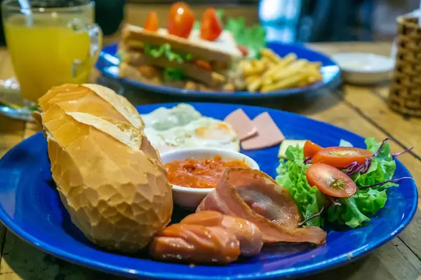 Baguette mit Wurst, Speck, Butter und Bohnen als Frühstück Nahaufnahme