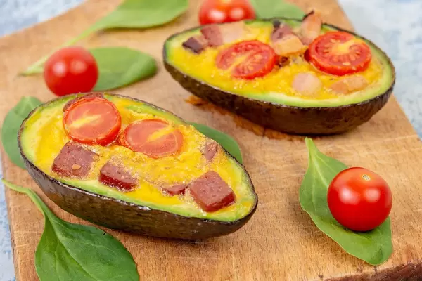 Baked Avocado with Eggs Cherry Tomato and Sausages on the wooden board (Flip 2019)