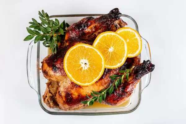Baked chicken stuffed apples with fresh orange in the baking dish on white, top view