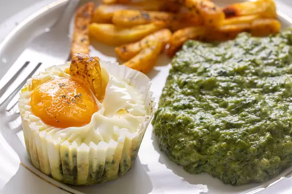 Baked Egg with Spinach and french fries on the plate
