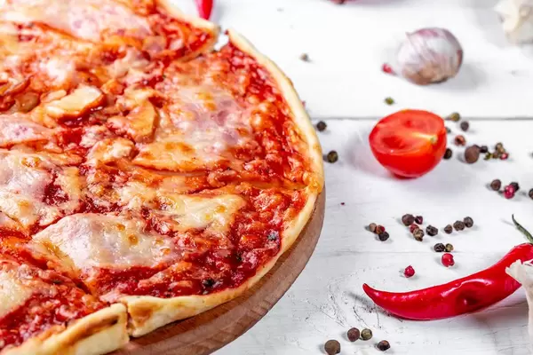 Baked pizza with spices on a white wooden table