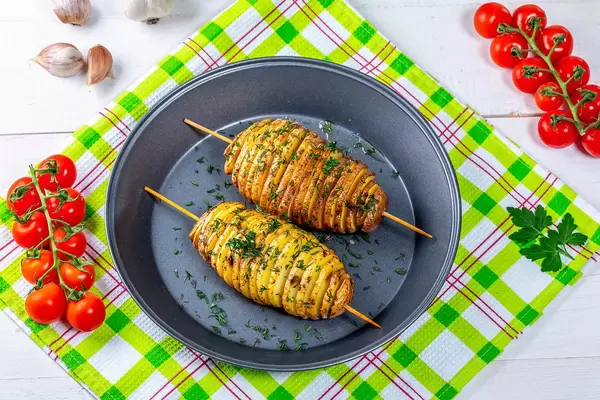 Baked potatoes on skewers with herbs and cherry tomatoes. Top view