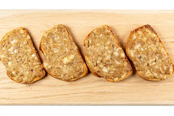 Baked sandwiches with fish on a wooden board, top view