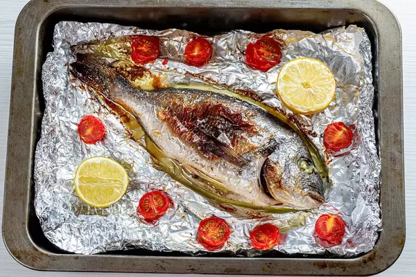 Baked with vegetables Dorado fish on foil in a baking sheet (Flip 2019)