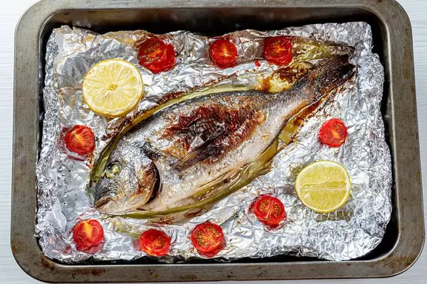 Baked with vegetables Dorado fish on foil in a baking sheet