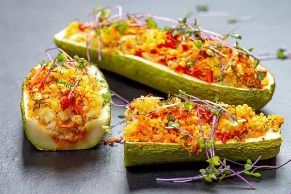 Baked zucchini with vegetables and couscous on a black background with micro green cabbage (Flip 2019)