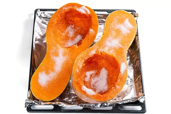 Baking tray with pumpkin halves and sugar, ready to bake