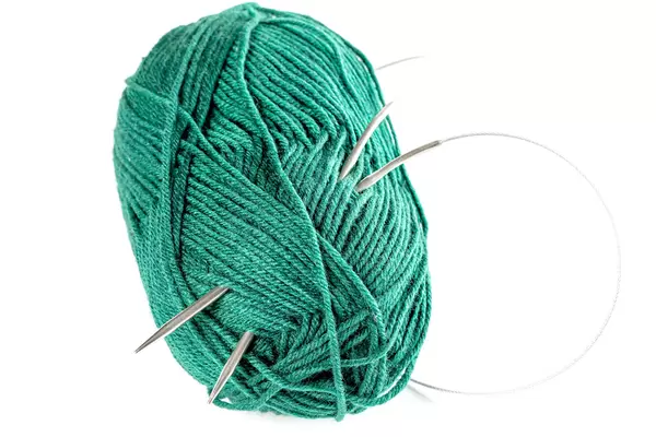 Ball of green knitting wool or yarn, with knitting needles