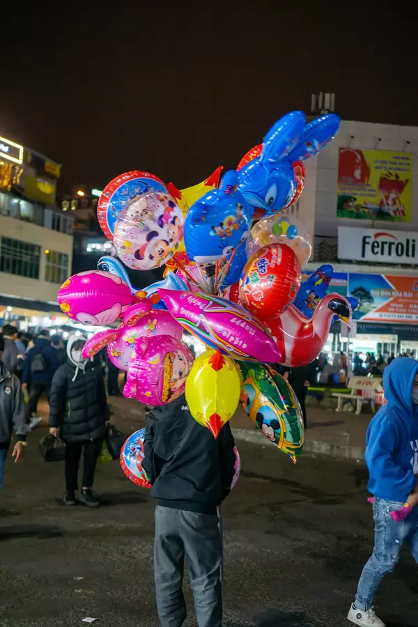 Balloon Seller selling various Balloons in Cartoon Designs at a Roundabout at the Dalat Night Market in Vietnam